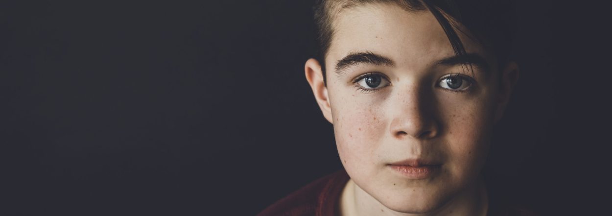 Portrait of confident boy standing against black background